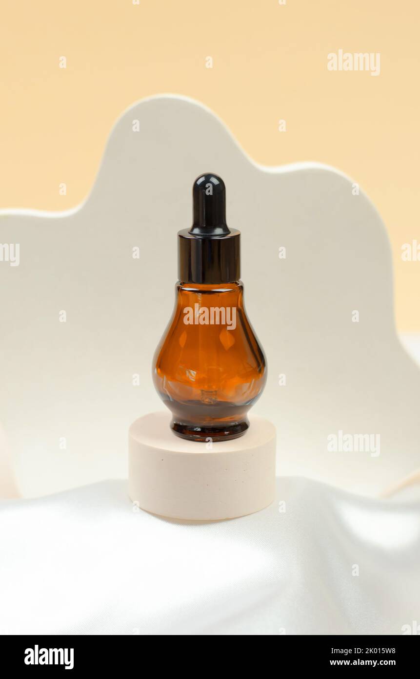 Natural essential oil or serum in a bottle with a pipette on a gray