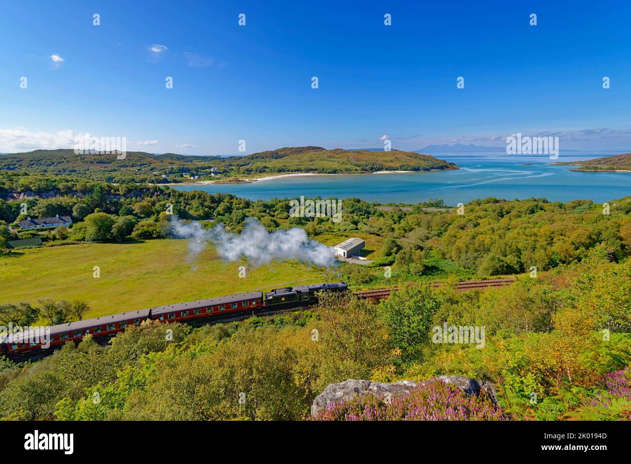 JACOBITE STEAM TRAIN ARRIVING AT MORAR BAY THE BLUE SEA AND ISLAND OF RUM IN THE DISTANCE Stock Photo