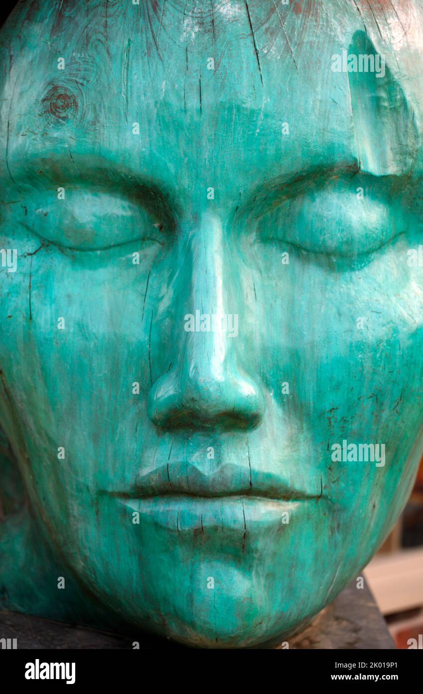 Large carved wooden face, painted Green or Aqua. An exhibit at the Symondsbury estate, Dorset. UK Stock Photo