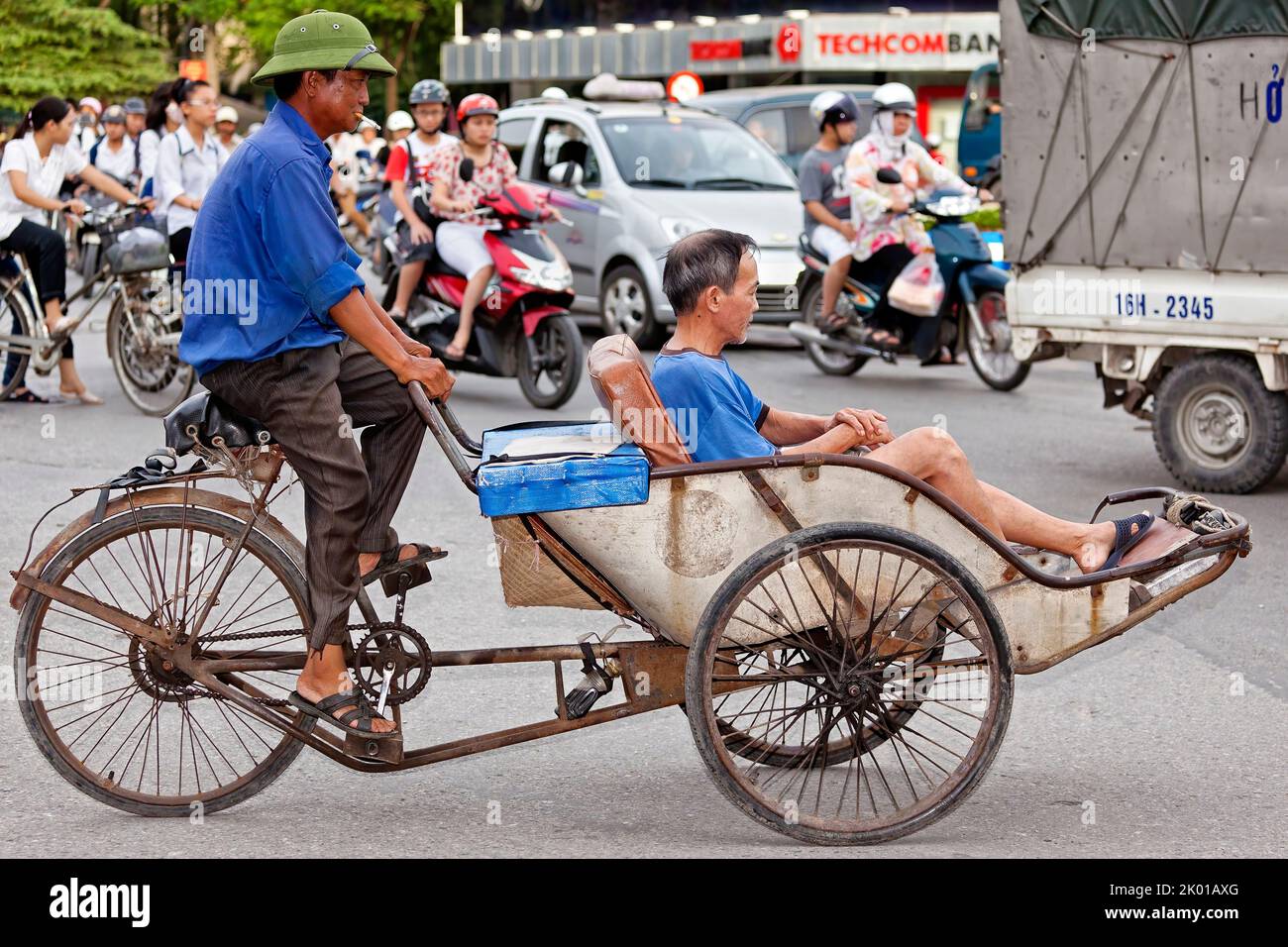 Vietnamese bicycle rickshaw, rider and passenger in traffic, Hai Phong, Vietnam Stock Photo