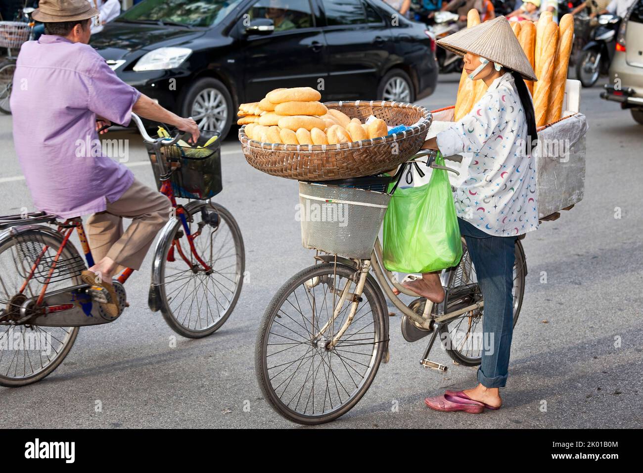 Vietnamese lady wearing bamboo hat selling French bread in the street, Hai Phong, Vietnam Stock Photo