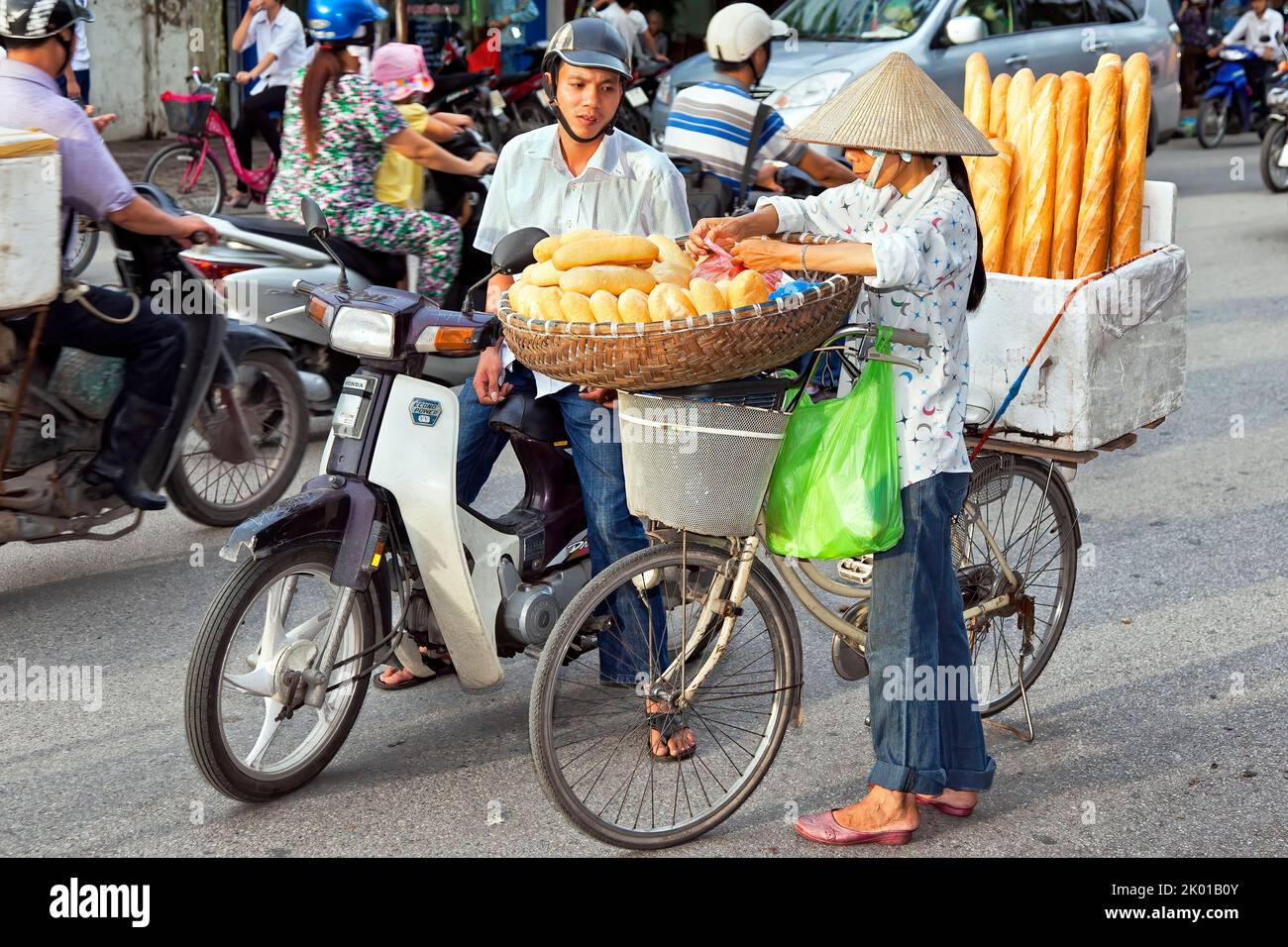 Vietnamese lady wearing bamboo hat selling French bread in the street, Hai Phong, Vietnam Stock Photo