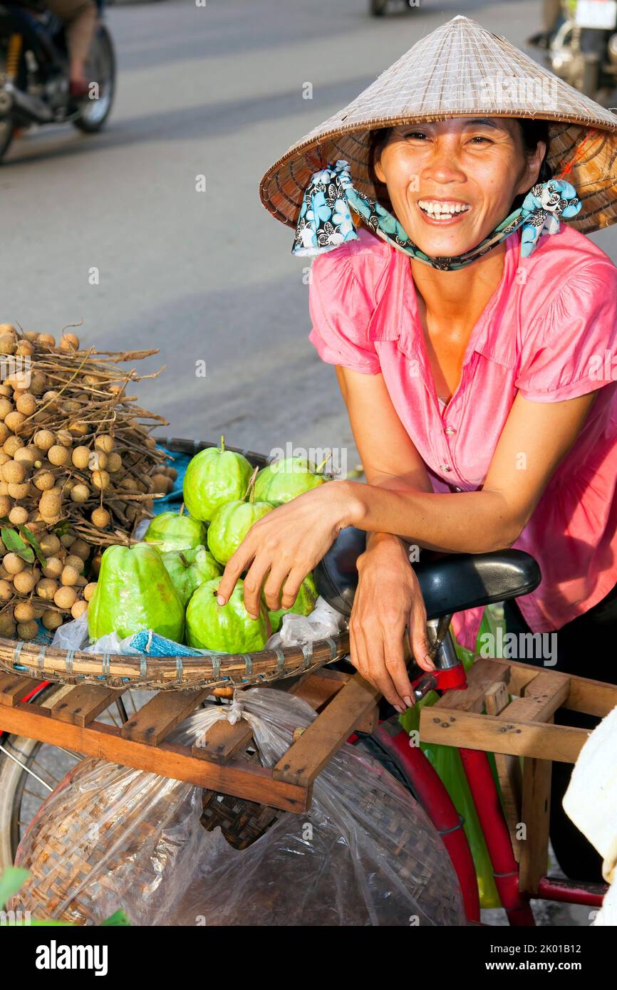 Vietnamese lady wearing bamboo hat selling fruit and vegetables in the street, Hai Phong, Vietnam Stock Photo