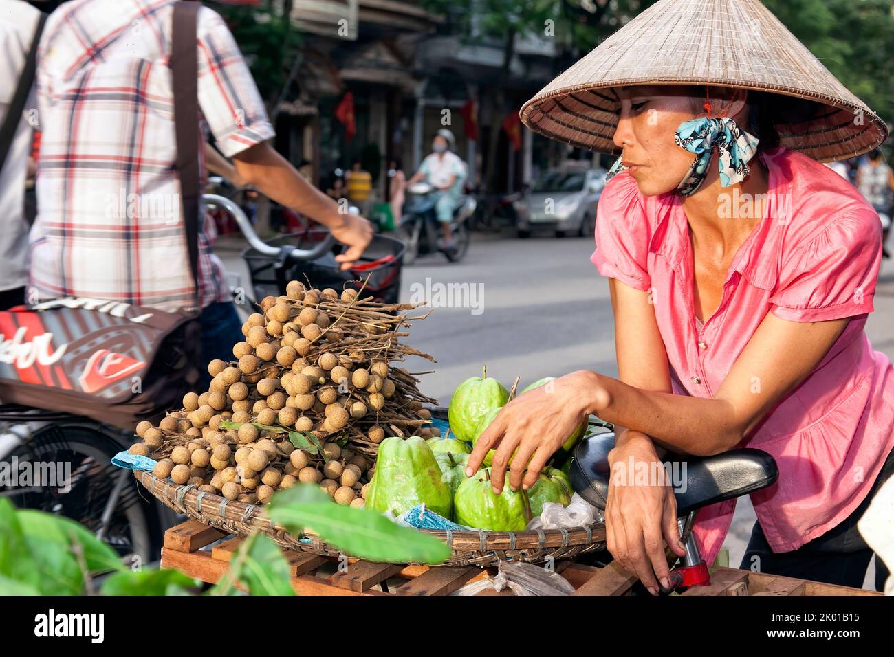 Vietnamese lady wearing bamboo hat selling fruit and vegetables in the street, Hai Phong, Vietnam Stock Photo