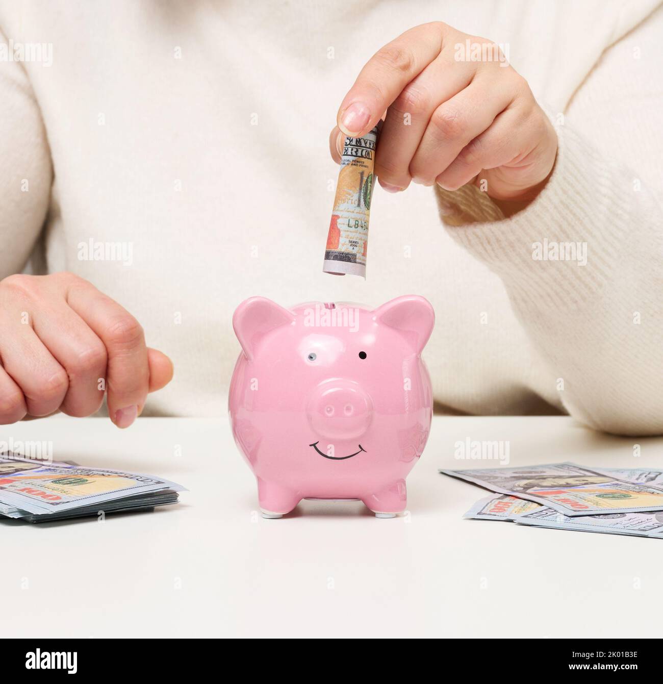 Pink ceramic piggy bank and woman with American paper money. Wealth