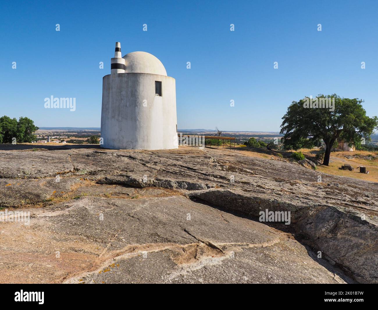 Well-preserved old windmill Alto de São Bento. White cylindrical building, built on a hill near the town of Evora on a large block of granite stone. Stock Photo