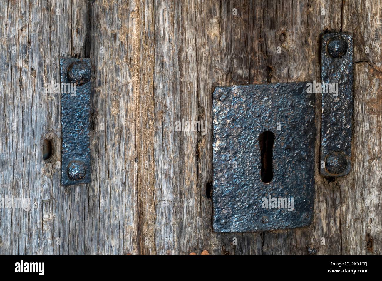 Antique church iron door furniture keyhole on a bleached oak door with rusting studs Stock Photo