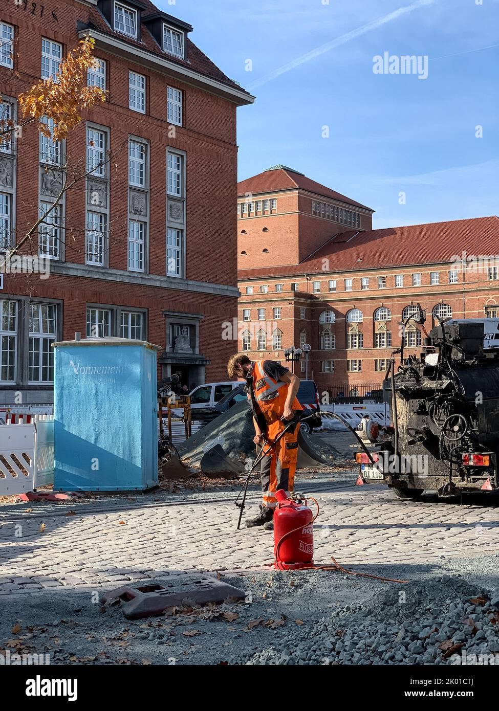 Pflasterarbeiten für Kopfsteipflaster in der Kieler Innenstadt ein Mann verfugt das Straßenpflaster mit Bitumen Stock Photo