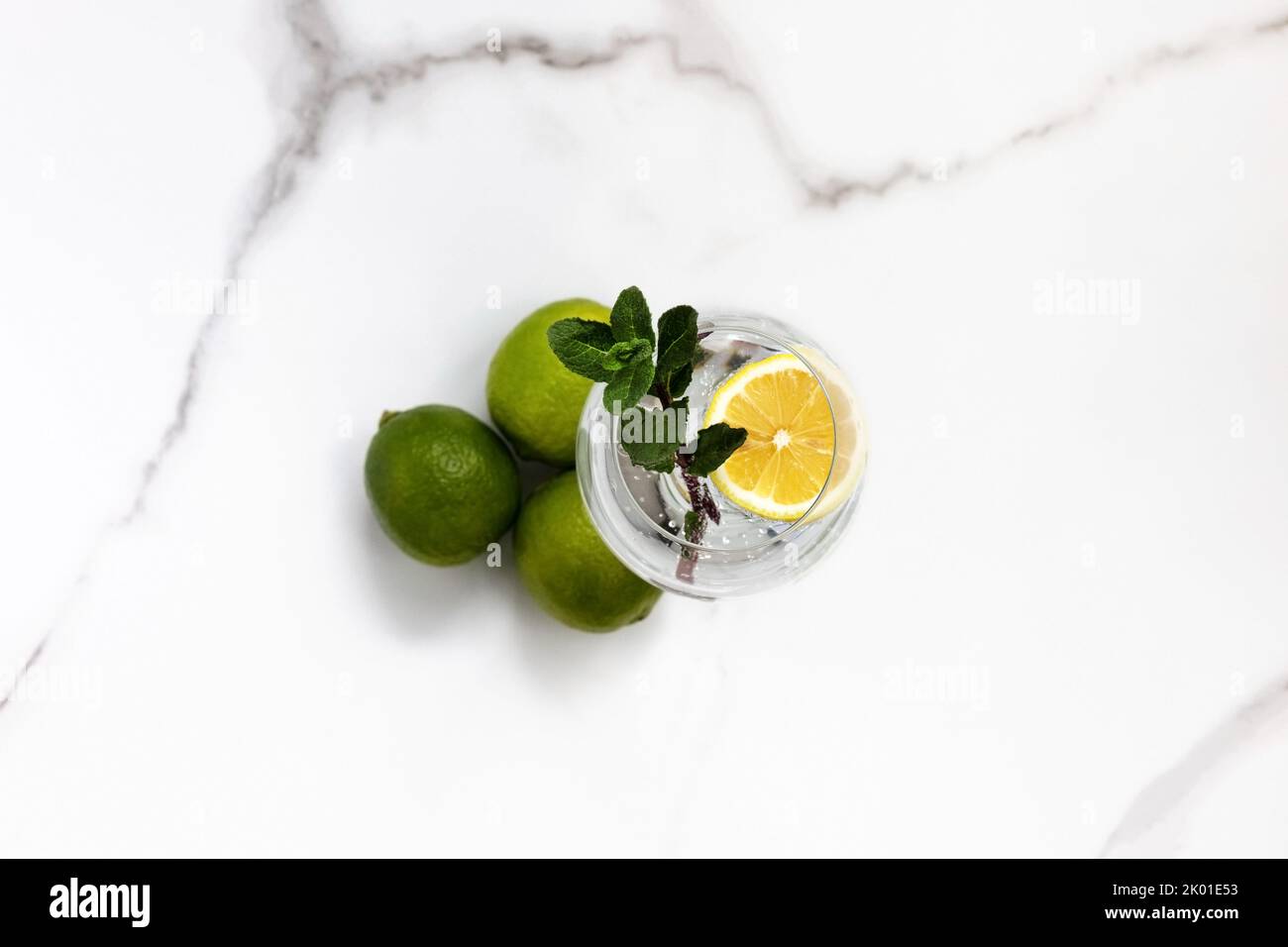 A glass of water, lemon and mint and lime on a white table for healthy life, energy, thermoregulation and normalization of digestion Stock Photo