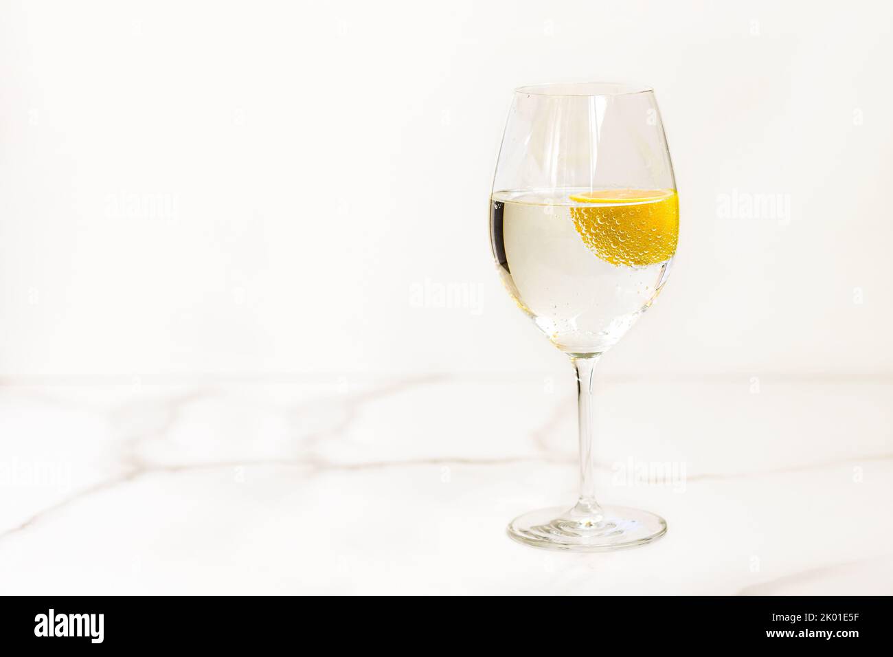 A glass of water with lemon on a light table for healthy life, energy ...