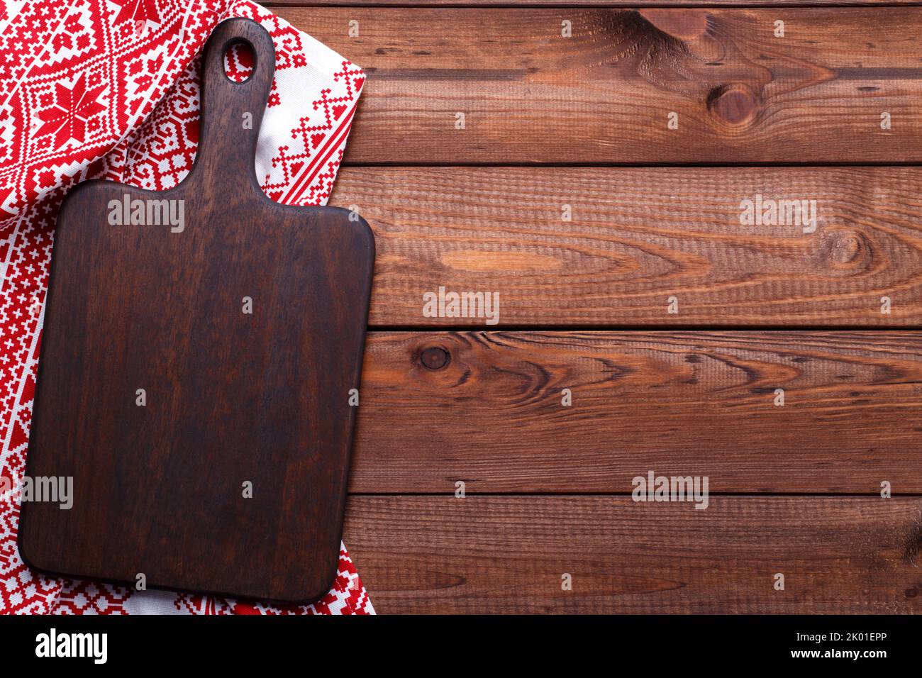 Brown wooden cutting board and red table cloth flat lay with copy space Stock Photo