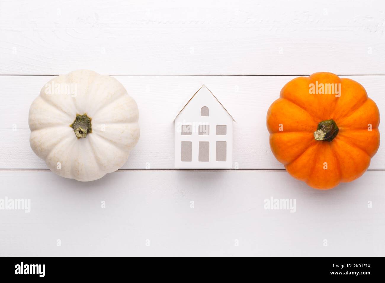 White and orange decorative pumpkins and white littel house toy on the white wooden background, flat lay with copy space Stock Photo