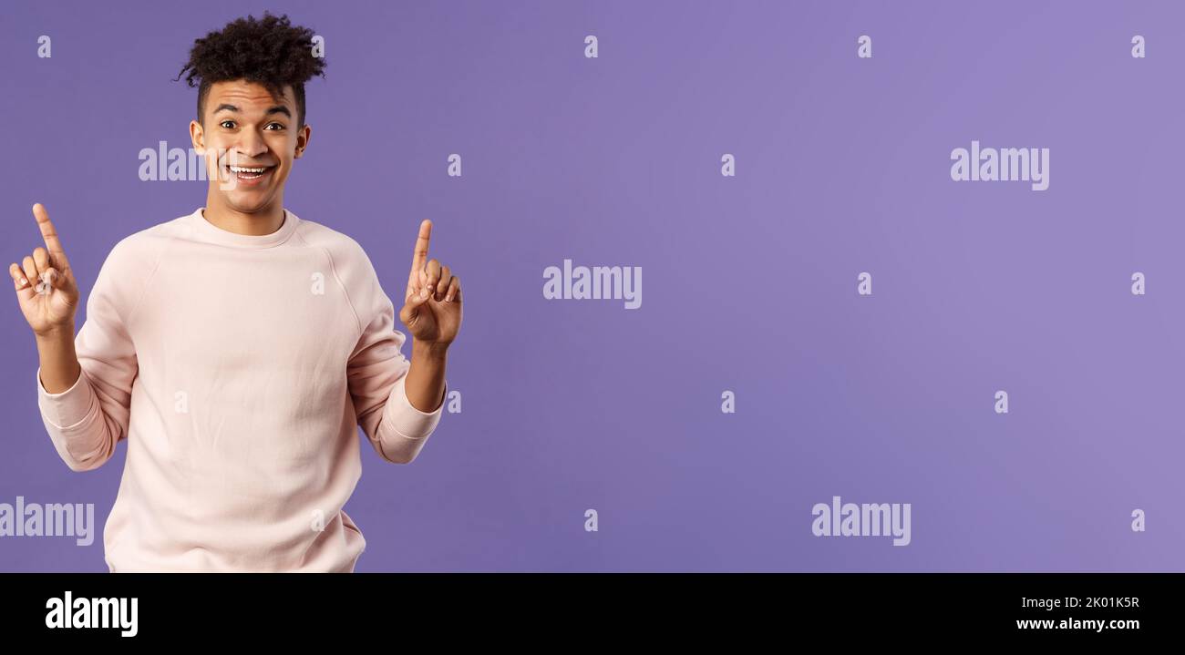 Portrait of charismatic lively young man heard about good deal, asking question intrigued, pointing fingers up, smiling upbeat at camera, look with Stock Photo