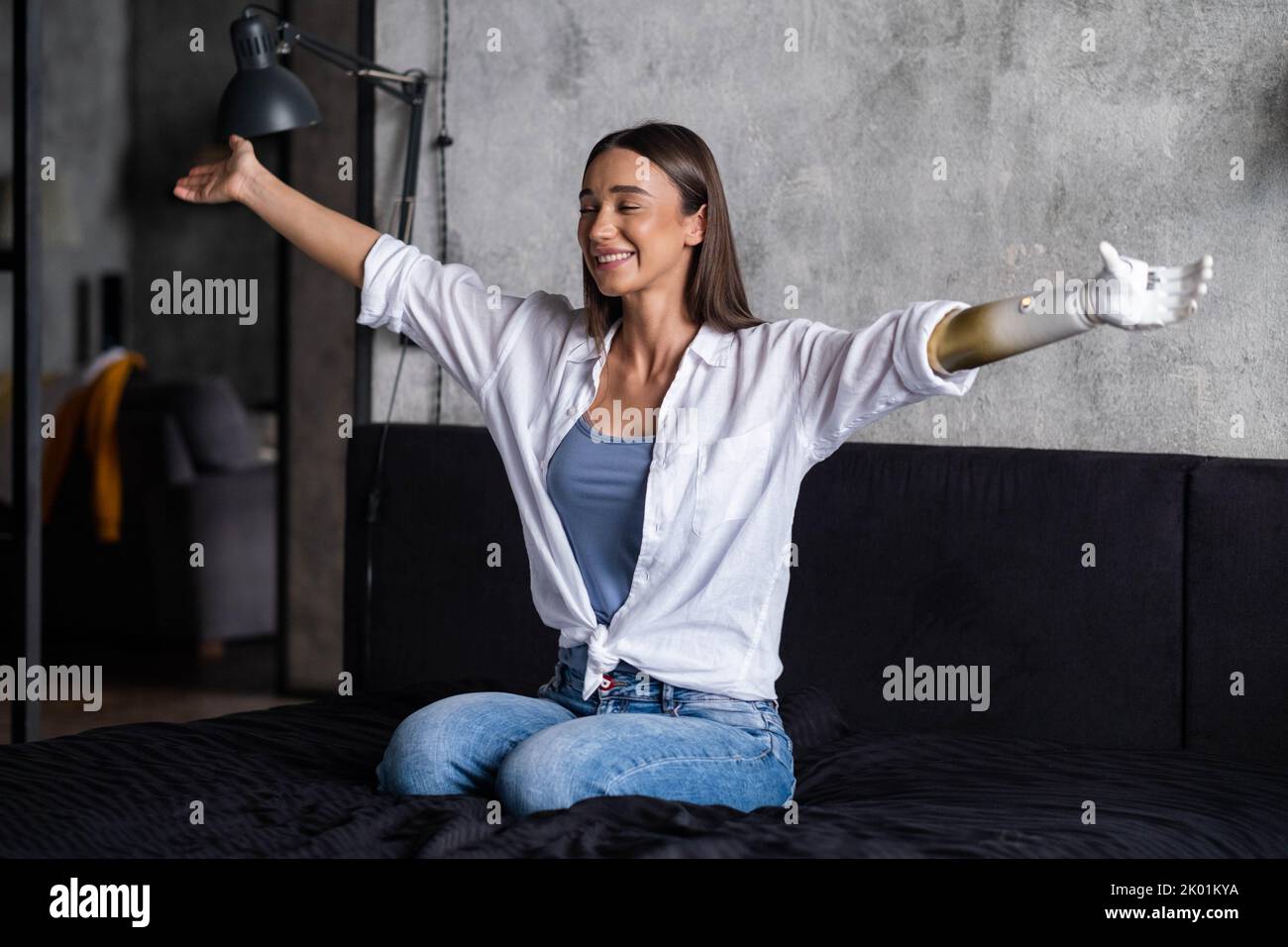 Portrait happy woman with prosthetic arm, girl with disability relaxing raising arms artificial prosthetic limb. Stock Photo