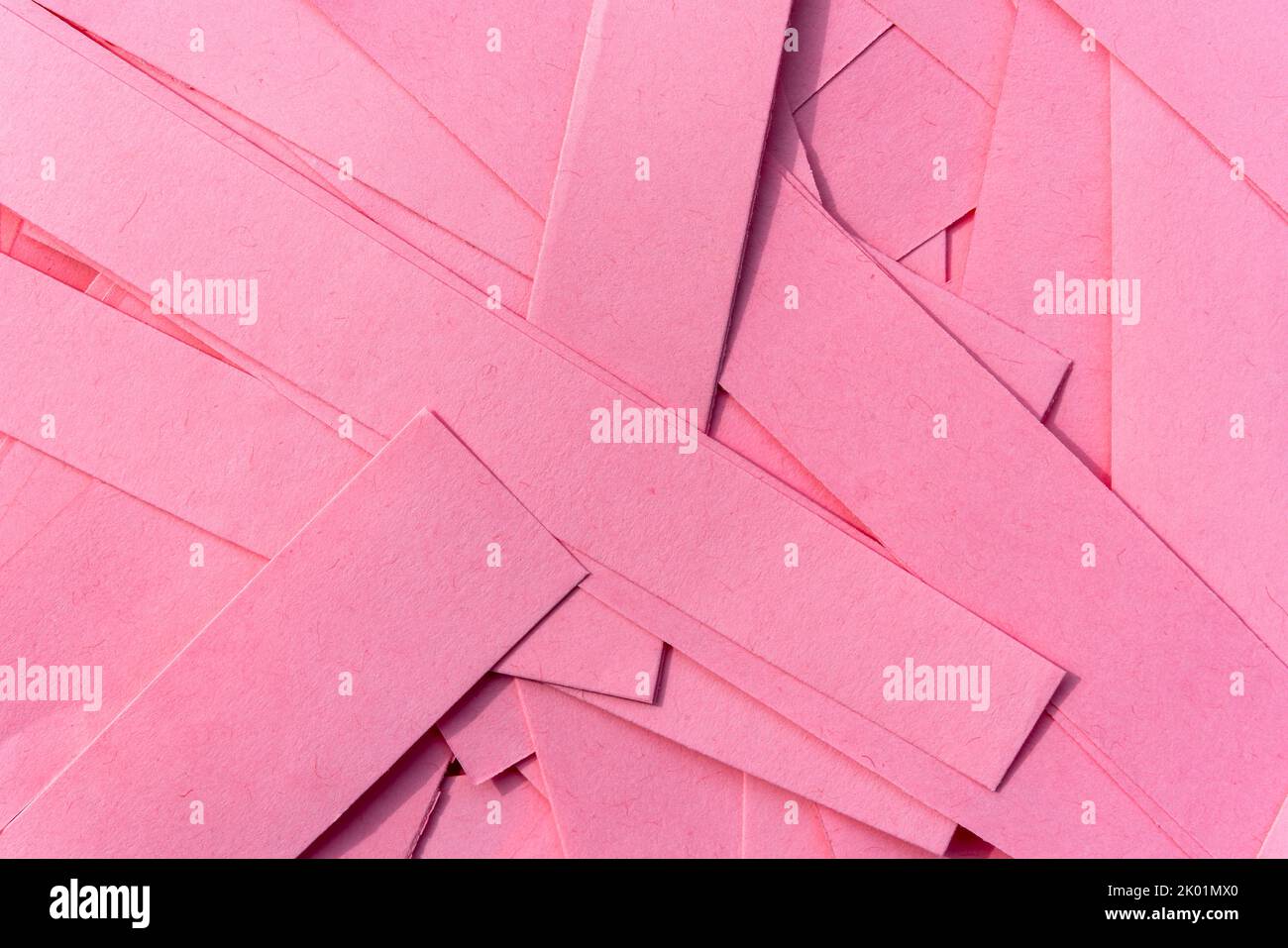 Pink paper texture background made from cut out strips of a recycled cardboard sheets stacked in a pile to give a natural design patten effect, stock Stock Photo