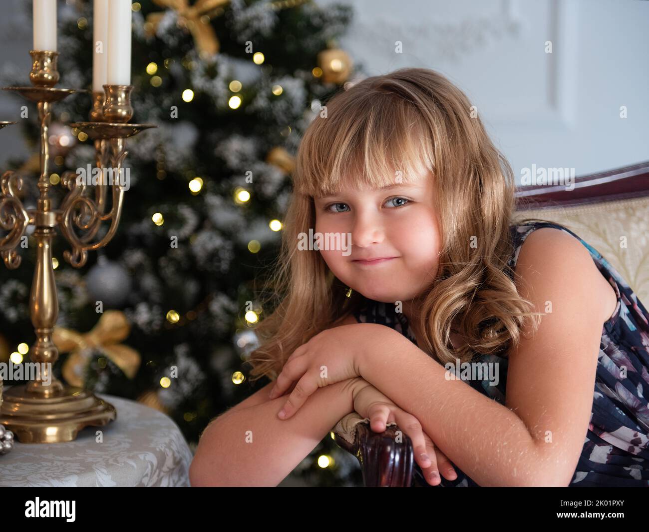 The little girl is sitting in a beautiful dress. New Year's decor. Stock Photo