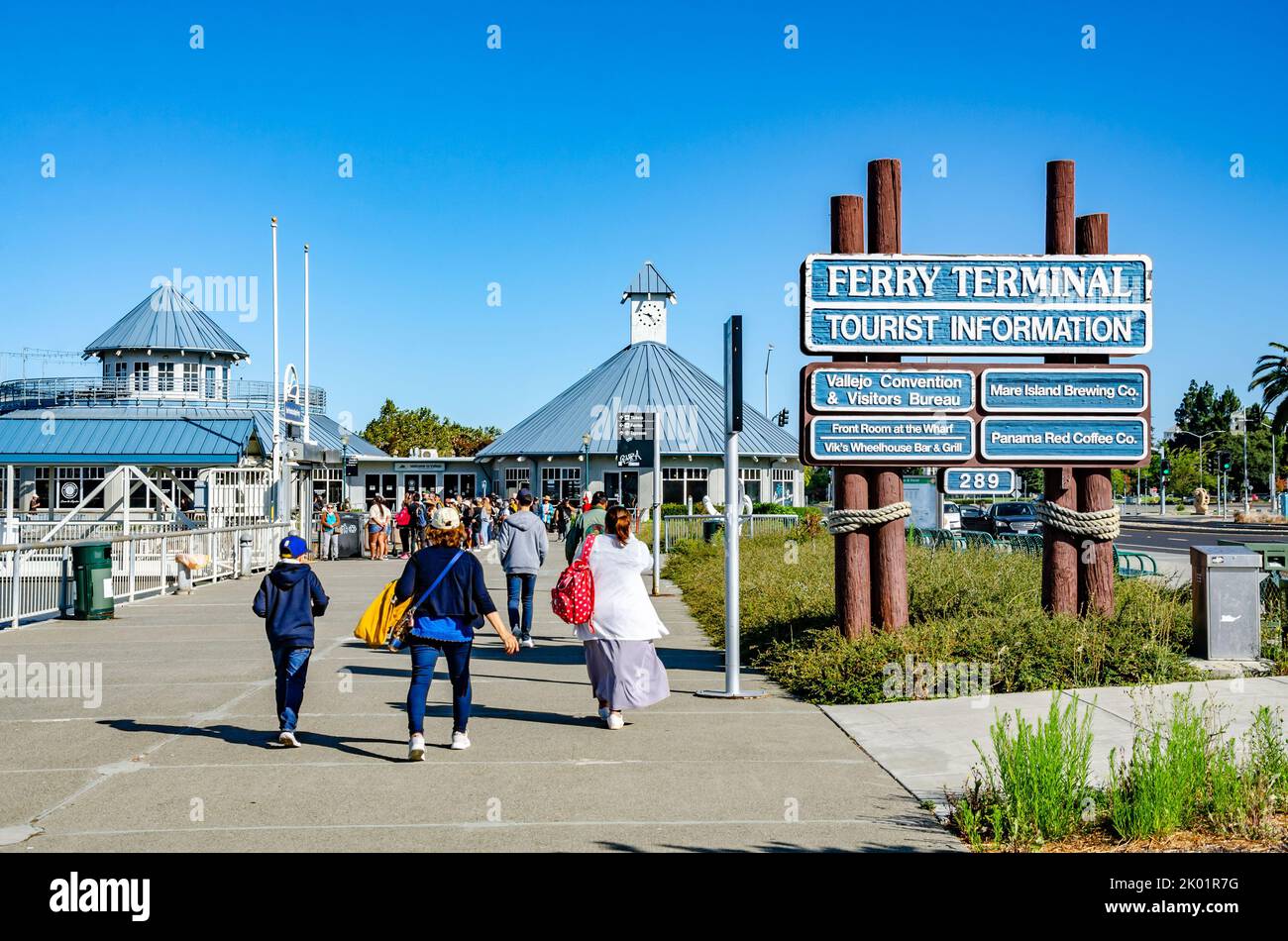 Visitors walk past tourist Information signs against a blue sky at Vallejo Ferry Terminal in California, USA Stock Photo
