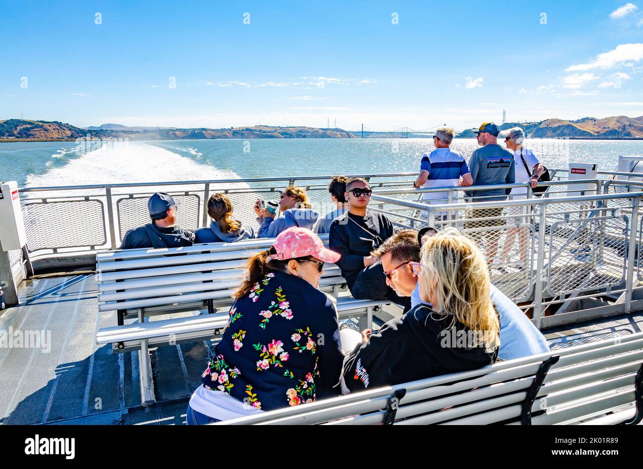 People sat on the rear, top deck of a San Francisco Bay Ferry sailing from Vallejo to San Francisco Stock Photo