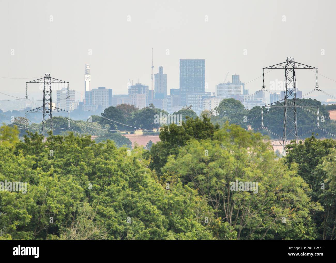 Powerlines feeding electricity to the City of Birmingham, UK. The cityscape beyond the powerlines shows the famous BT tower in the city centre. Stock Photo