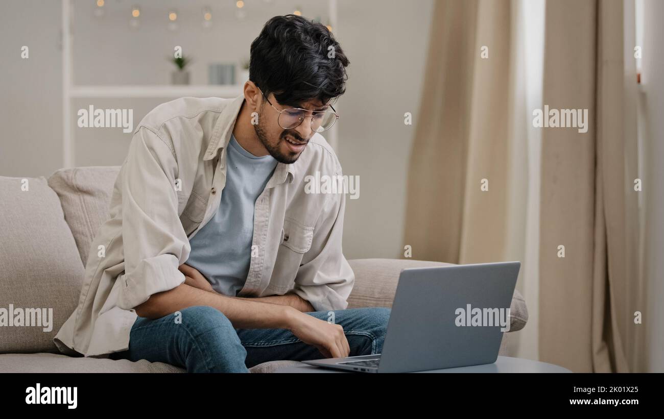 Ill arabic man bearded guy with glasses feels stress overwork cranial pressure massages weight on head suffering from headache migraine sighing Stock Photo