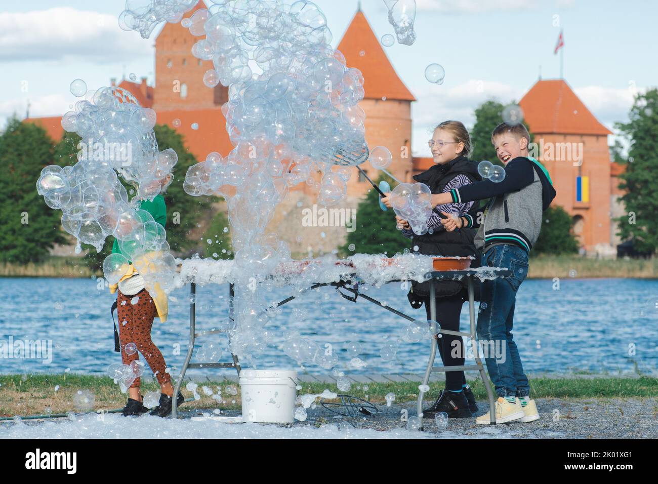 Happy children playing outdoor near a castle on a sunny day with soap bubbles Stock Photo