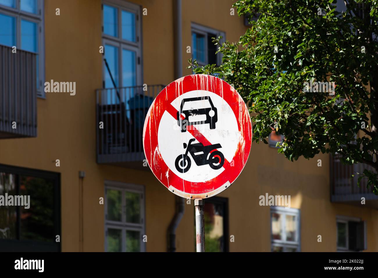 Red and white no motor vehicles sign on the street in the city with yellow building in the background Stock Photo