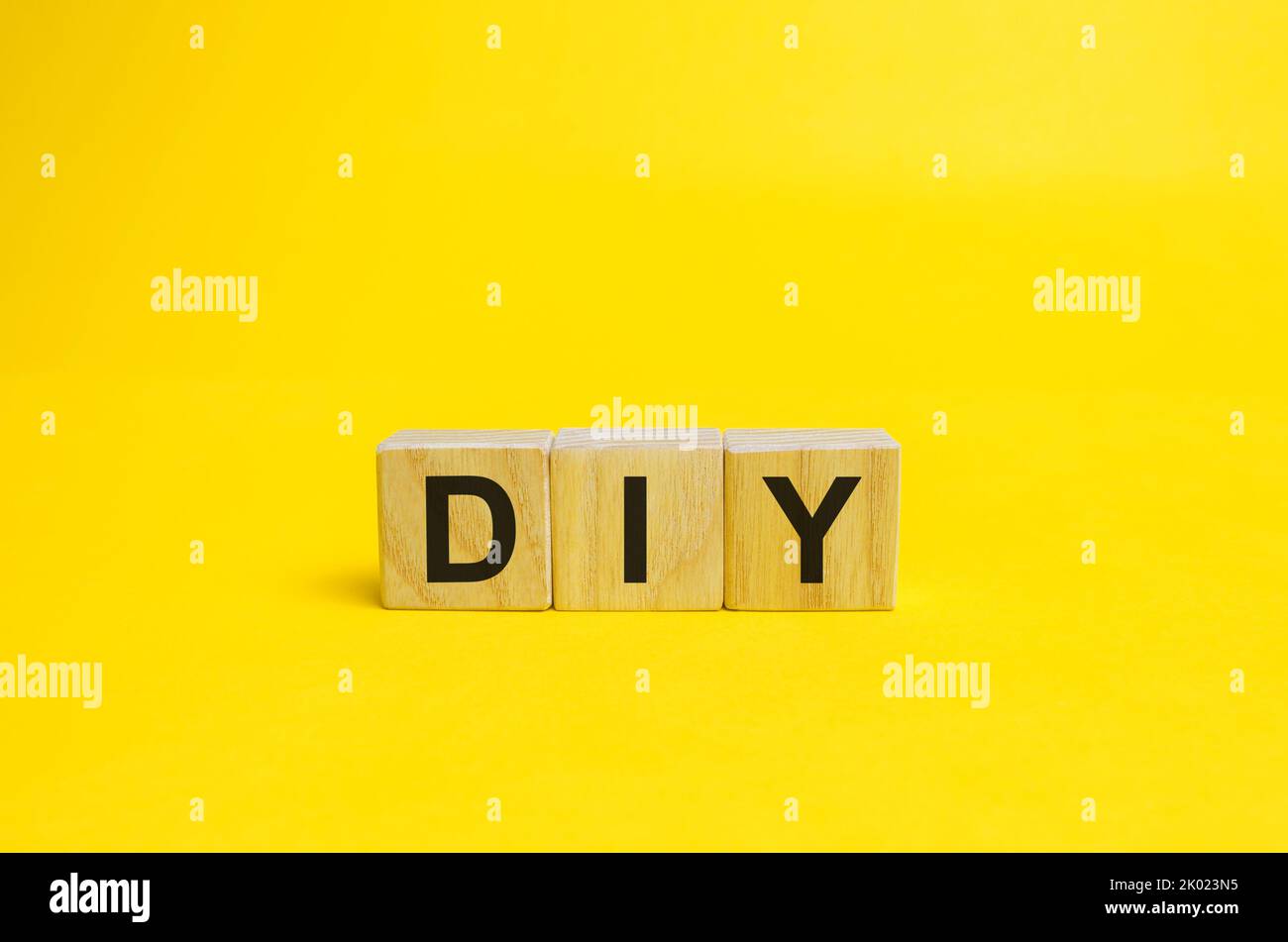 Wooden blocks with the word DIY - Do It Yourself concept. The method of self-creation of things without the help of professionals. yellow background Stock Photo