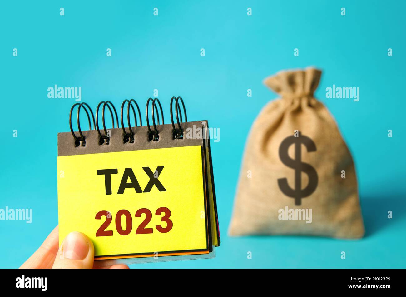 Notes with word Taxes 2023 and money bag. The concept of paying the tax rate. Taxation, taxes burden. Pay off debts. Property income annual taxes Stock Photo