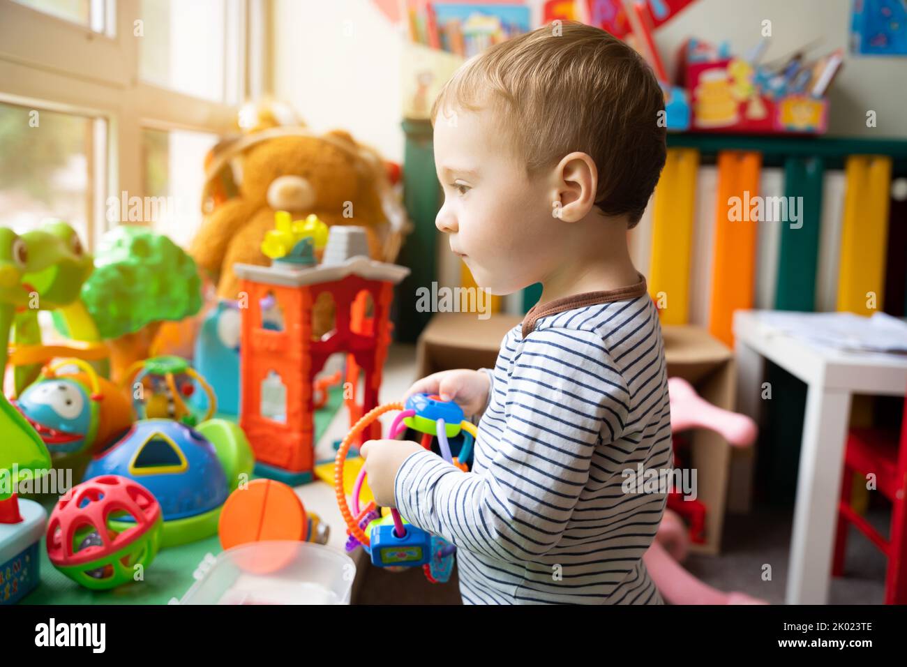 Toddler boy plays with educational toys in the children's room. The study of colors and the development of tactility. Child one and a half years - two Stock Photo