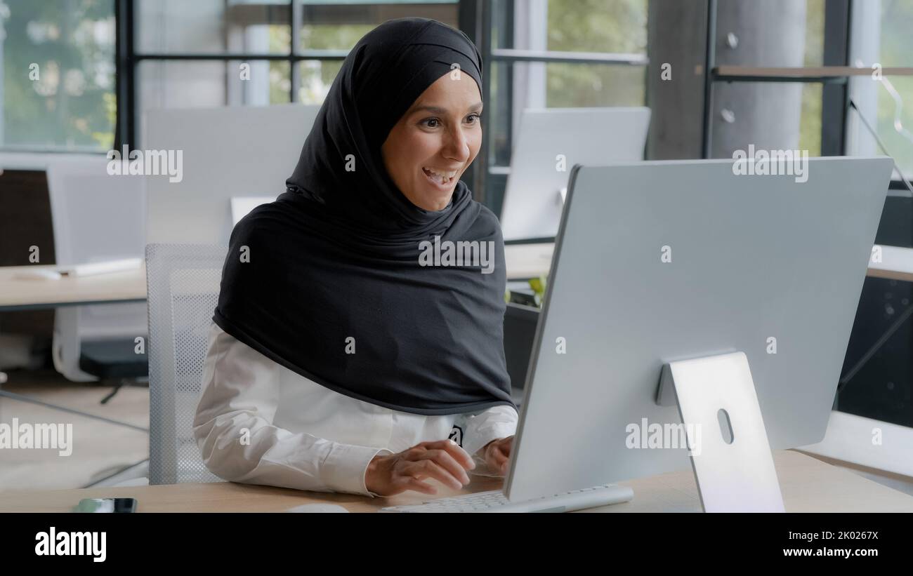 Excited arab businesswoman feeling winner celebrating success rejoicing in victory looking at computer screen winning online video game overjoyed girl Stock Photo