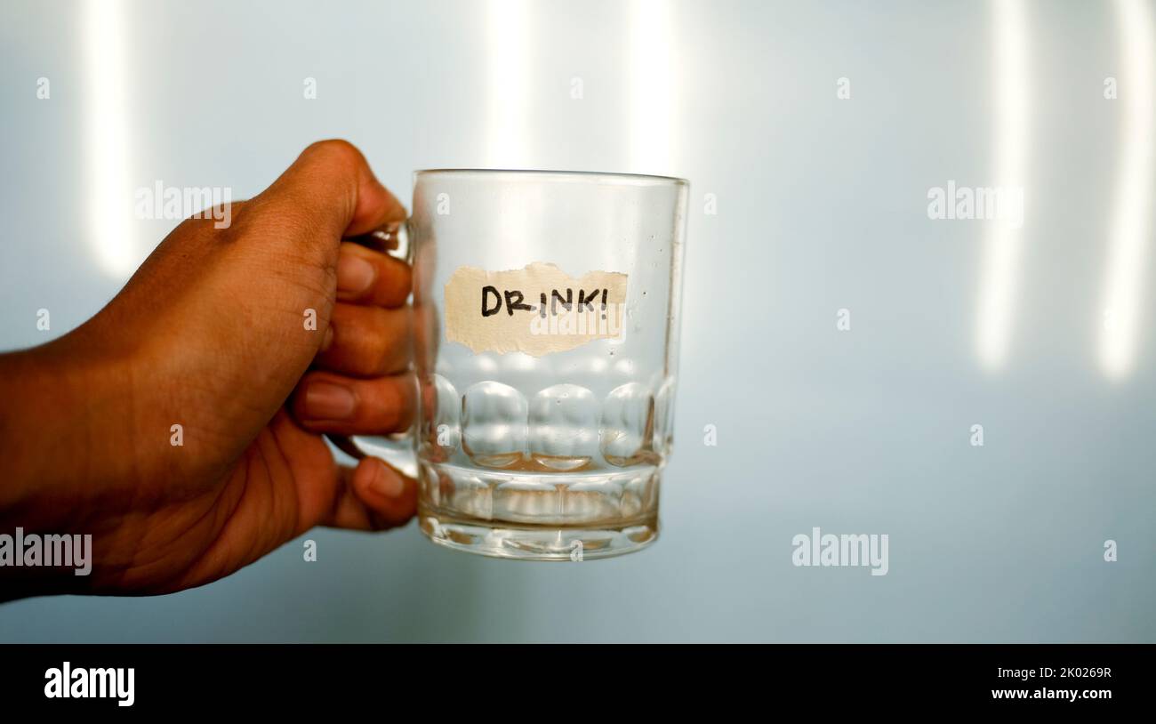 close up hand holding empty drinking glass with text word drink written