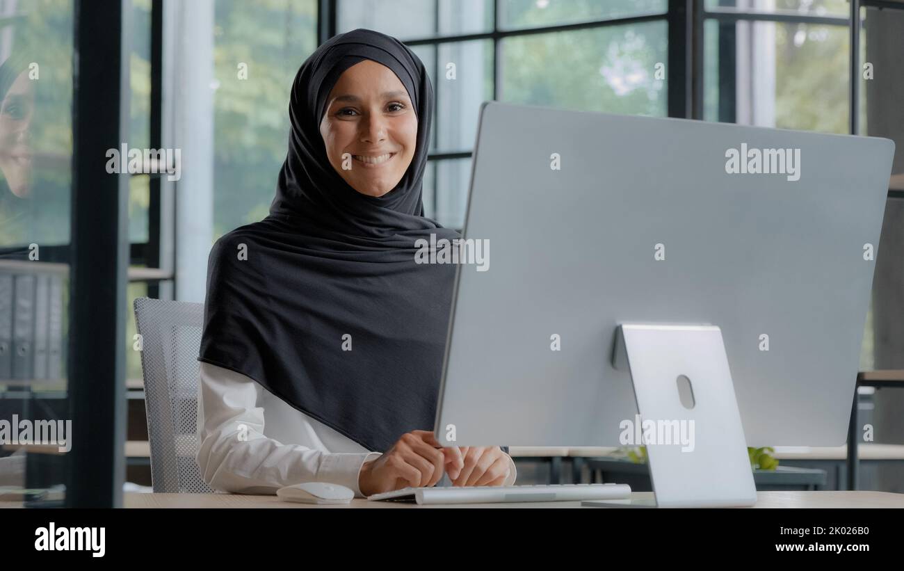 Confident successful elegant arab businesswoman typing on computer attractive muslim female in hijab professional worker experienced manager Stock Photo