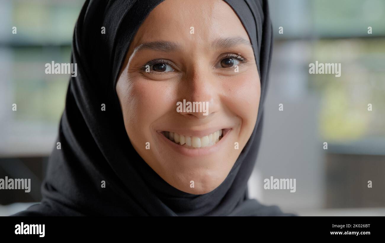 Headshot of young attractive arab woman in hijab looking at camera beautiful muslim girl with natural make-up posing indoors portrait happy islamic Stock Photo