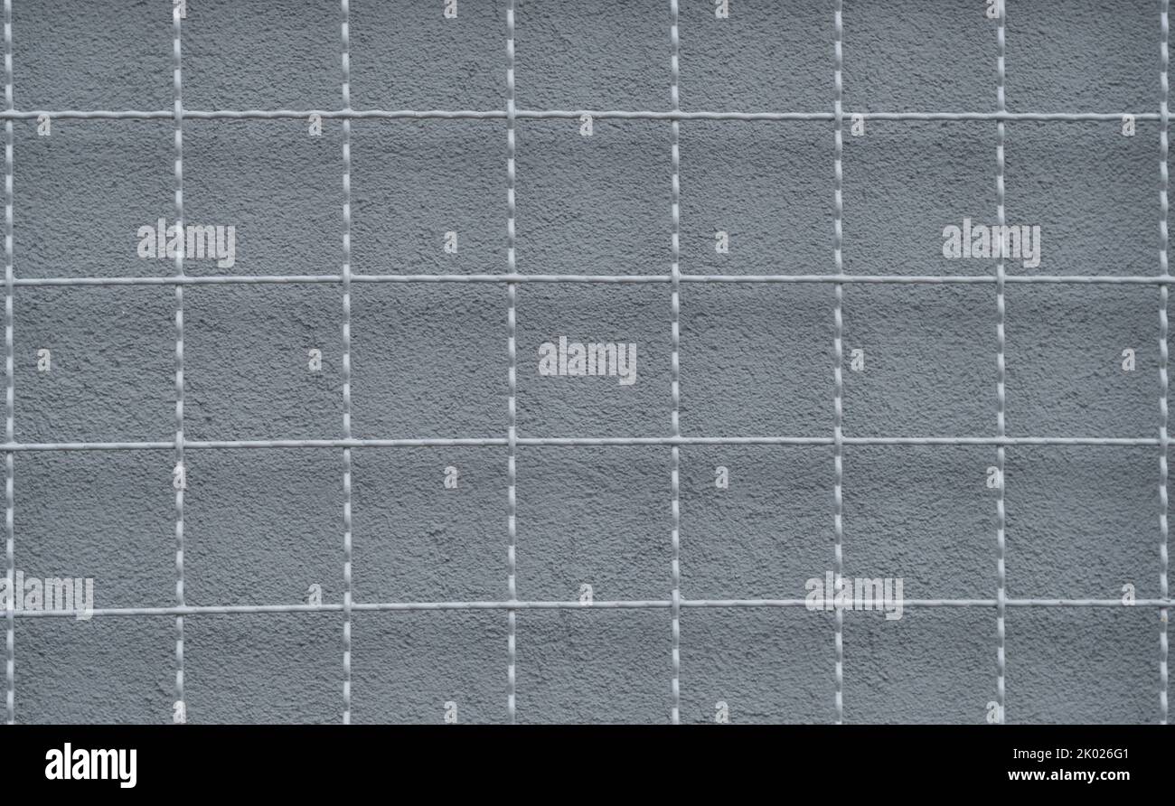 a metal grid and a gray wall behind it 2 Stock Photo