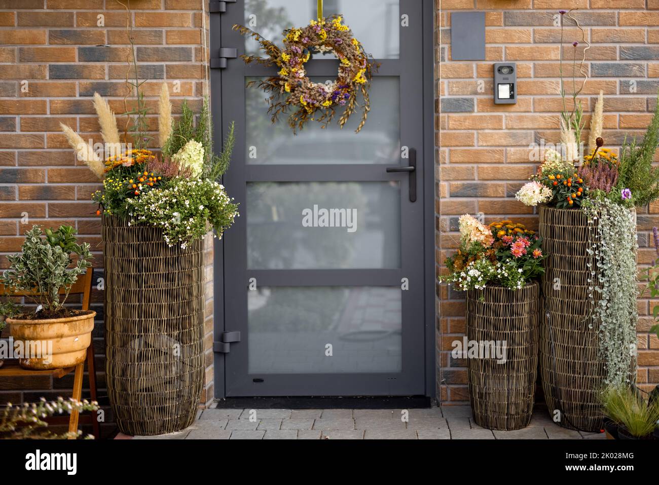 Beautiful porch of residential house decorated for autumn with flowers and wreath hanging on the door Stock Photo