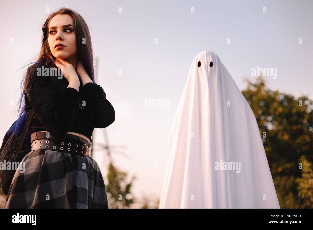 Young woman looking away while standing with ghost outdoors during Halloween Stock Photo