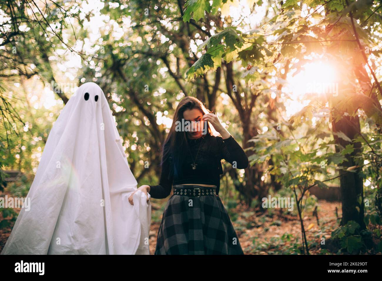 Teenage girl walking by the hand with ghost in forest during Halloween Stock Photo