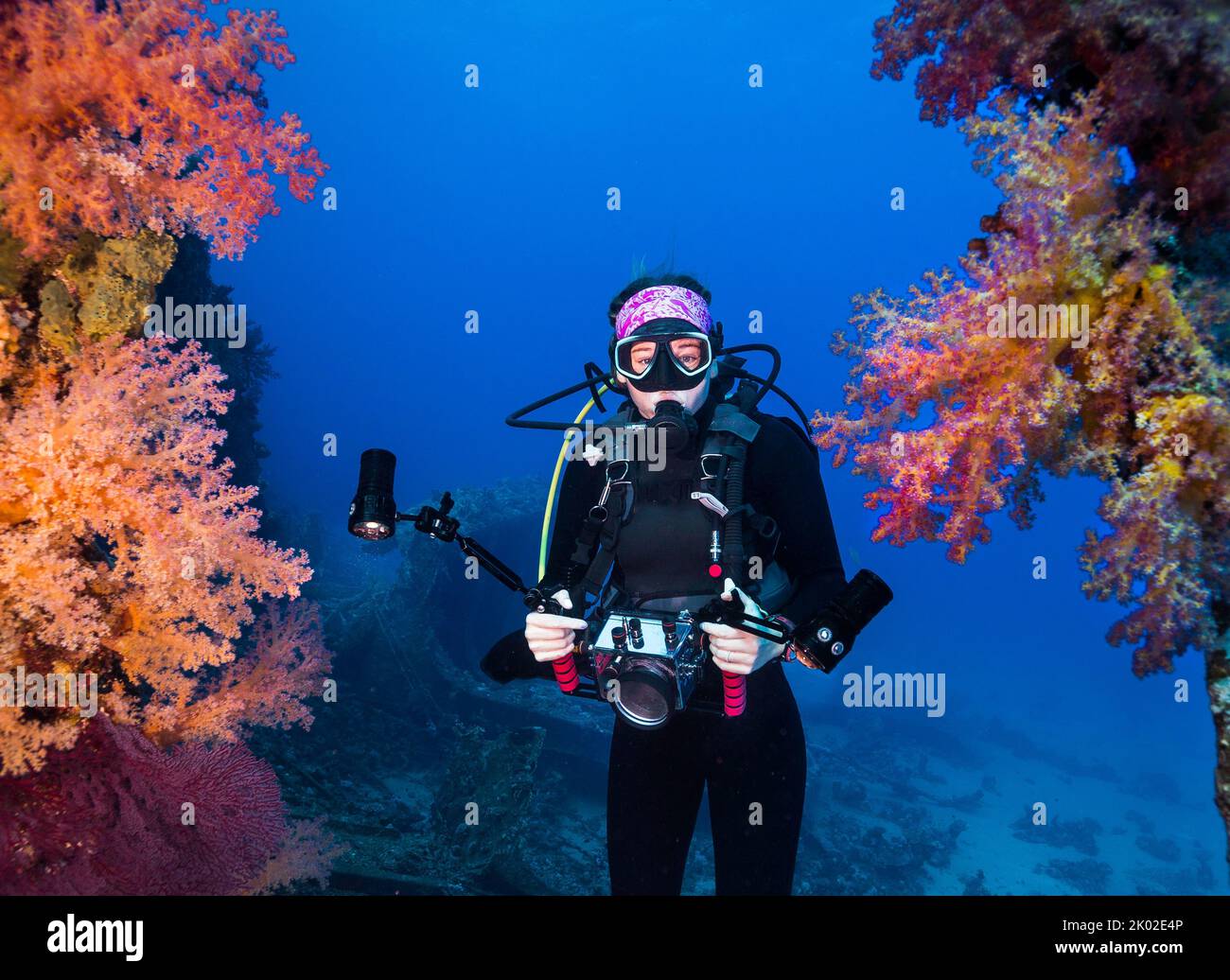 An underwater photographer holding her camera swimming between some