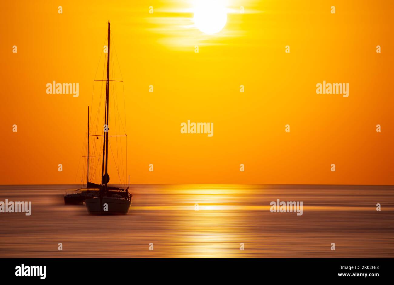 Sailing boat in sunset or sunrise sky over sea with a stunning tropical ...