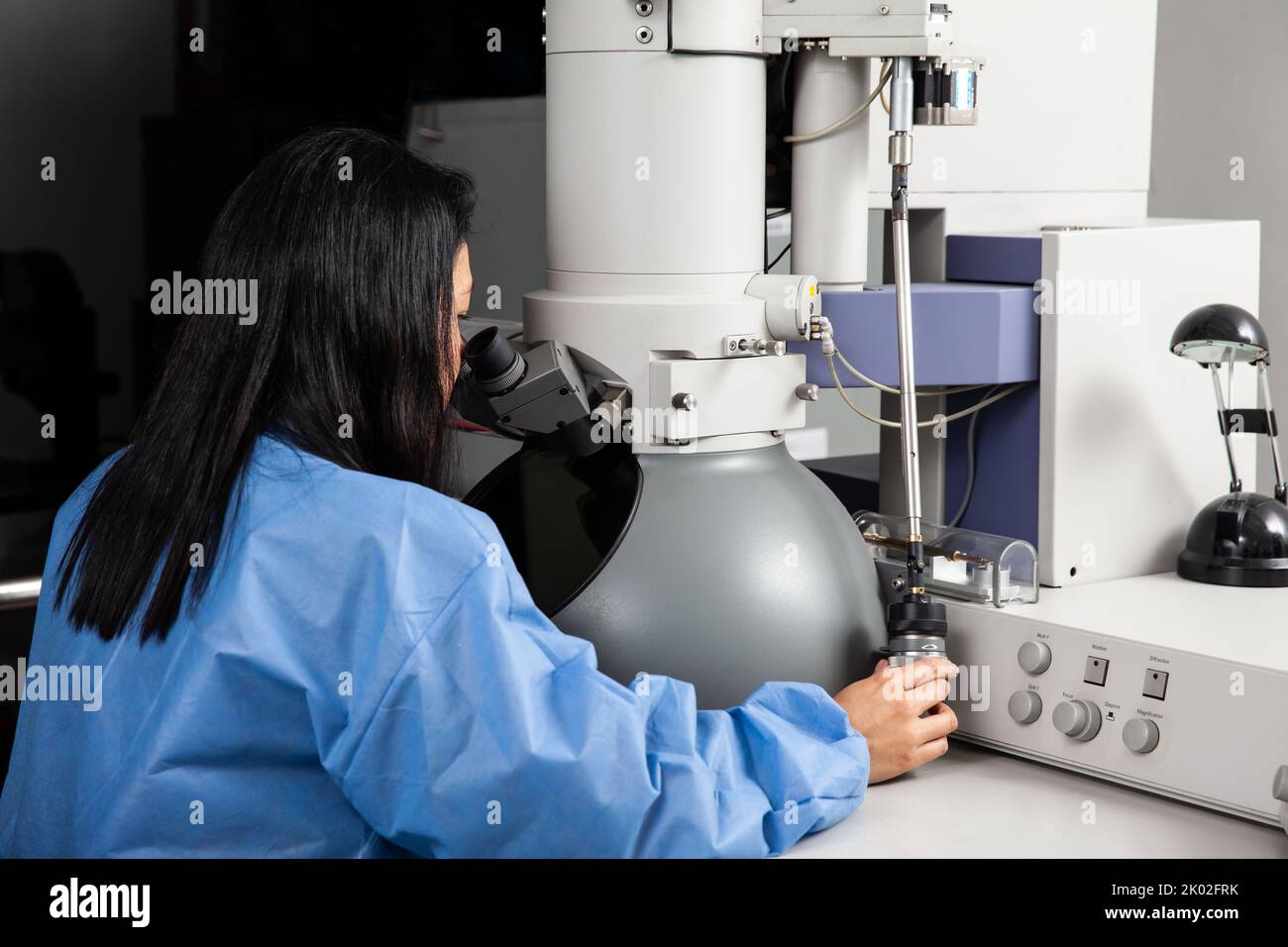 Young female scientist working at the laboratory with an electron microscope Stock Photo