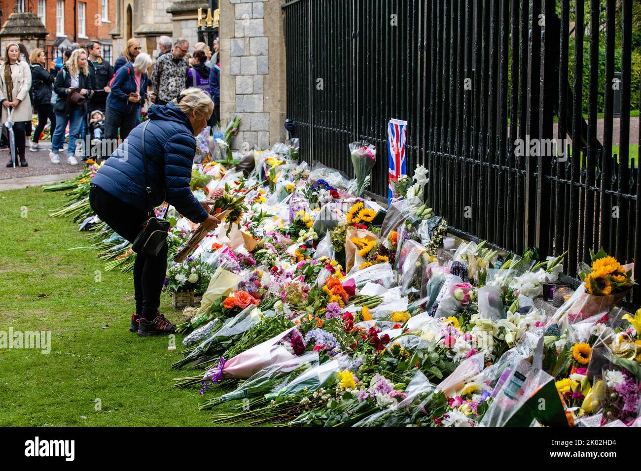 Windsor, UK. 9th September, 2022. A woman leaves a floral tribute outside Cambridge Gate at Windsor Castle a day after the death of Queen Elizabeth II. Queen Elizabeth II, the UK's longest-serving monarch, died at Balmoral aged 96 after a reign lasting 70 years. Credit: Mark Kerrison/Alamy Live News Stock Photo