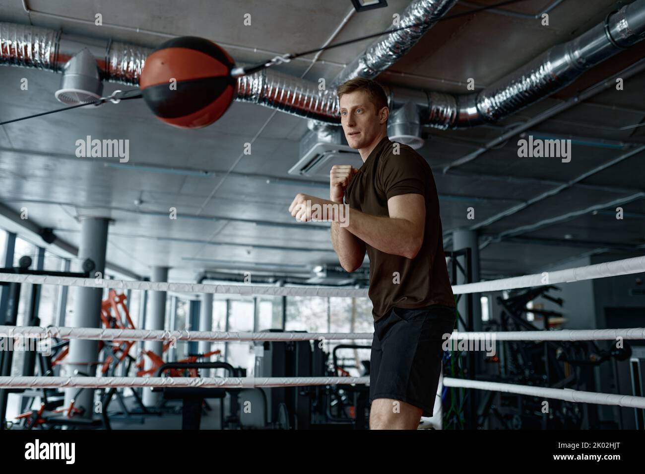 Young boxer trains with punching bag in gym Stock Photo