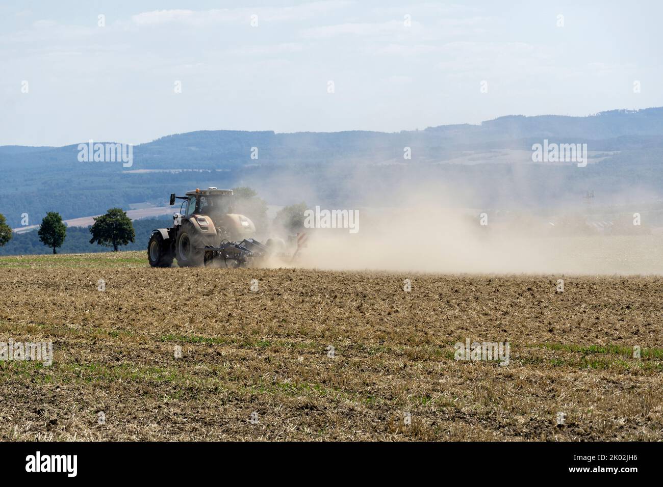 Tractor with plow on a dry field in Germany in the state of Hesse Stock Photo