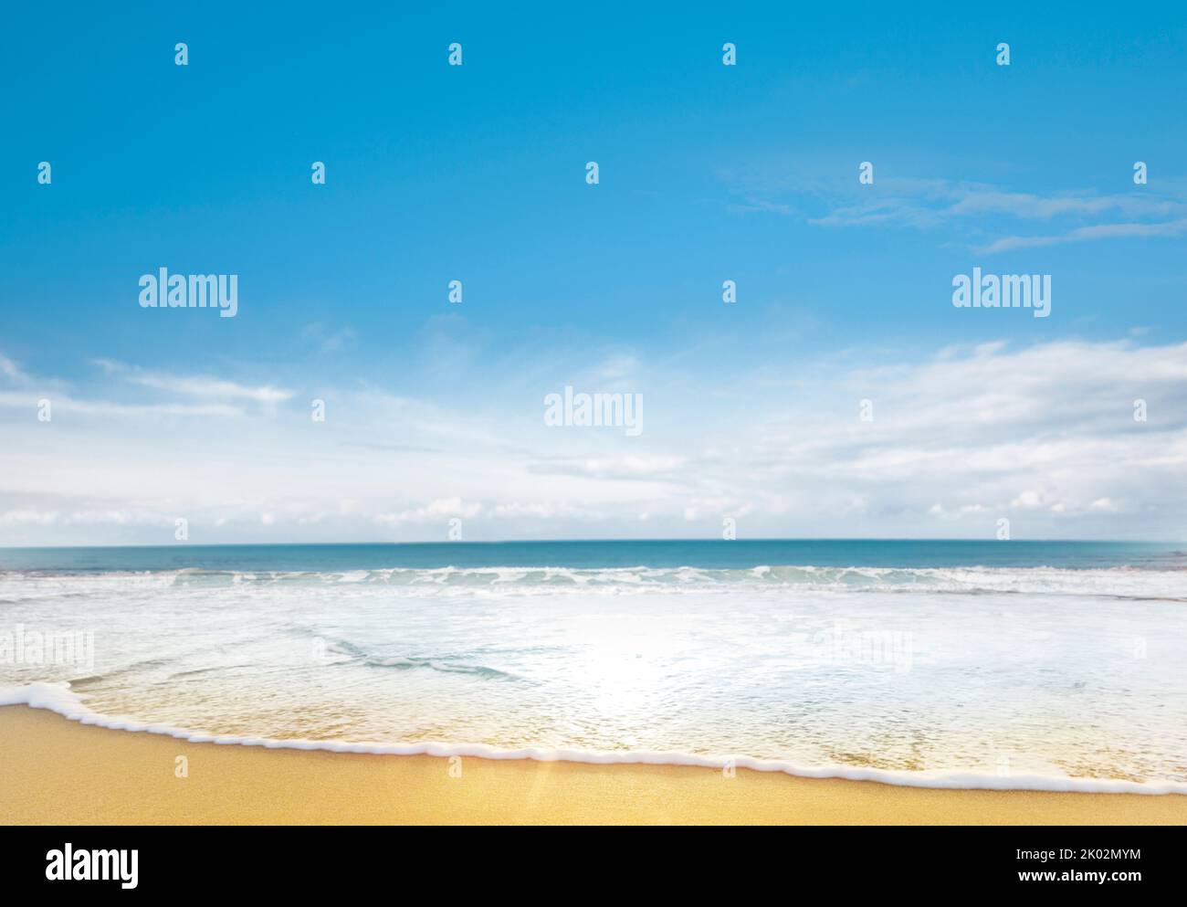Wave on sandy beach in front of blue sea Stock Photo