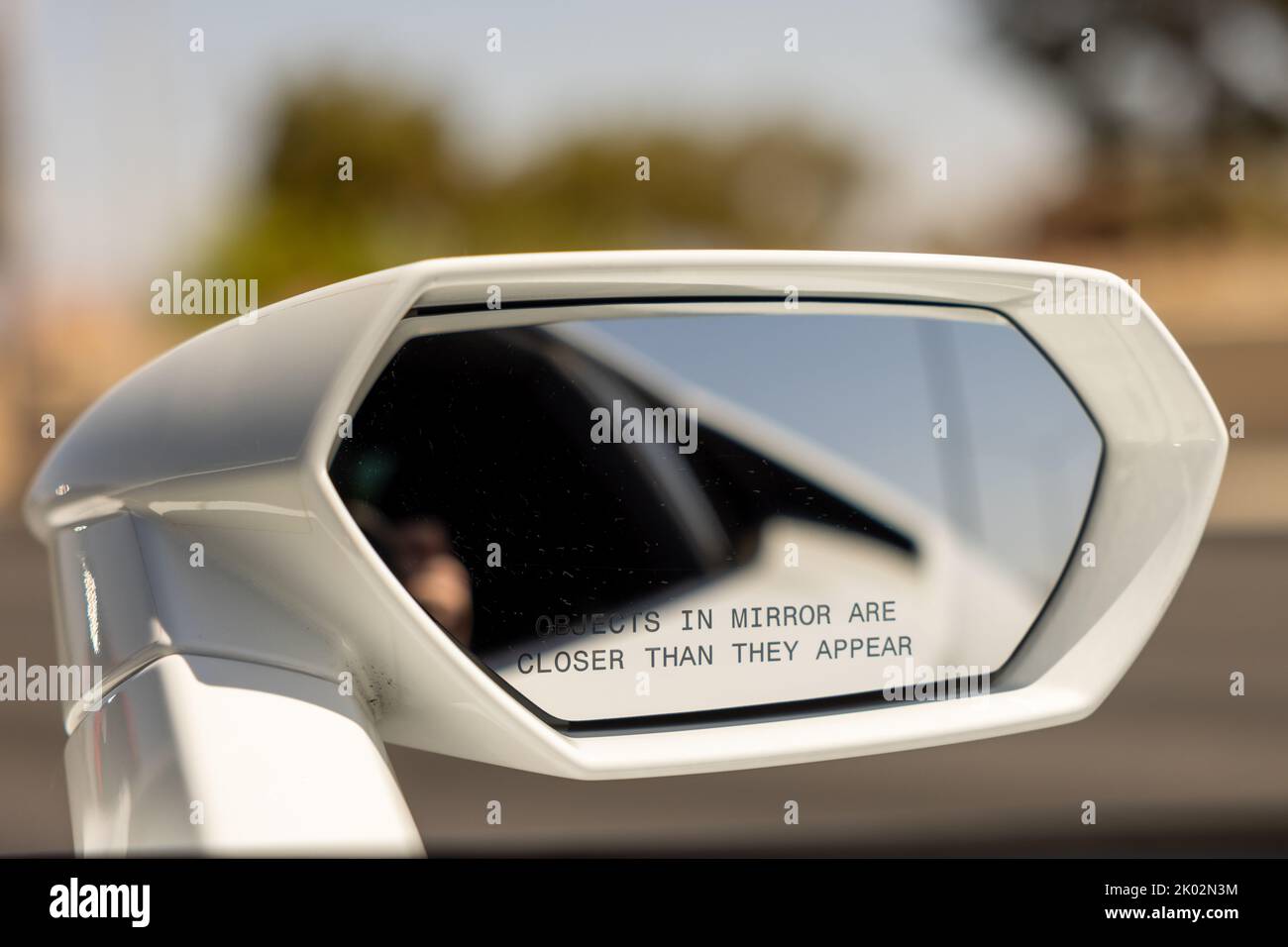A closeup of a rearview mirror with "objects in the mirror are closer than they appear" writing