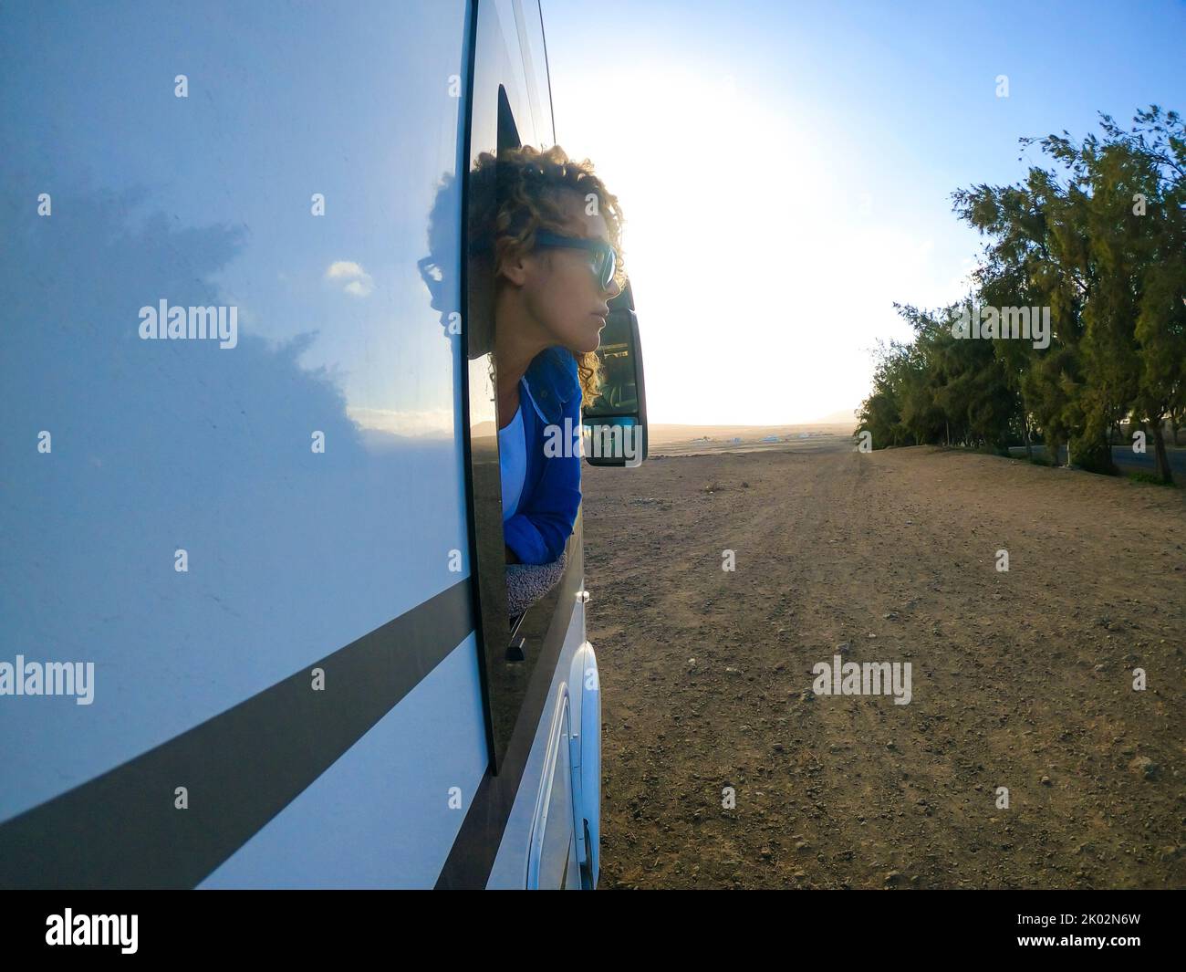 View of a woman outside the window of a camper van. Concept of travel on rented rv vehicle and enjoyin leisure in holiday vacation on the road. Freedom and alternative home off grid lifestyle Stock Photo
