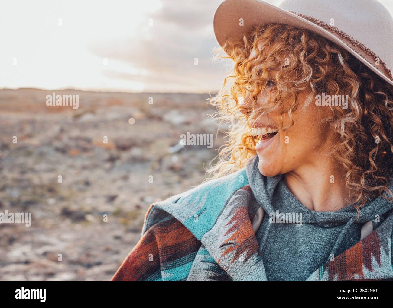 Side portrait of overjoyed and excited cheerful pretty woman with curly blonde hair and hat have fun in outdoor travel leisure activity. Tourist female people smile and laugh a lot in country side Stock Photo