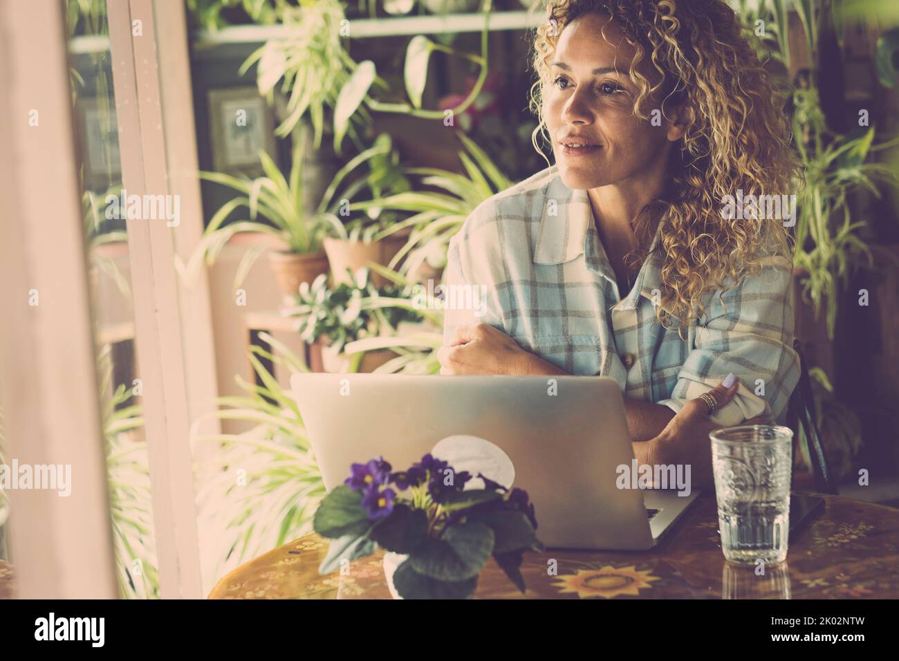 Serene people after work online with laptop computer. Cheerful confident portrait of adult woman enjoying break after business digital job. Concept of people in smart working sitting at the table Stock Photo