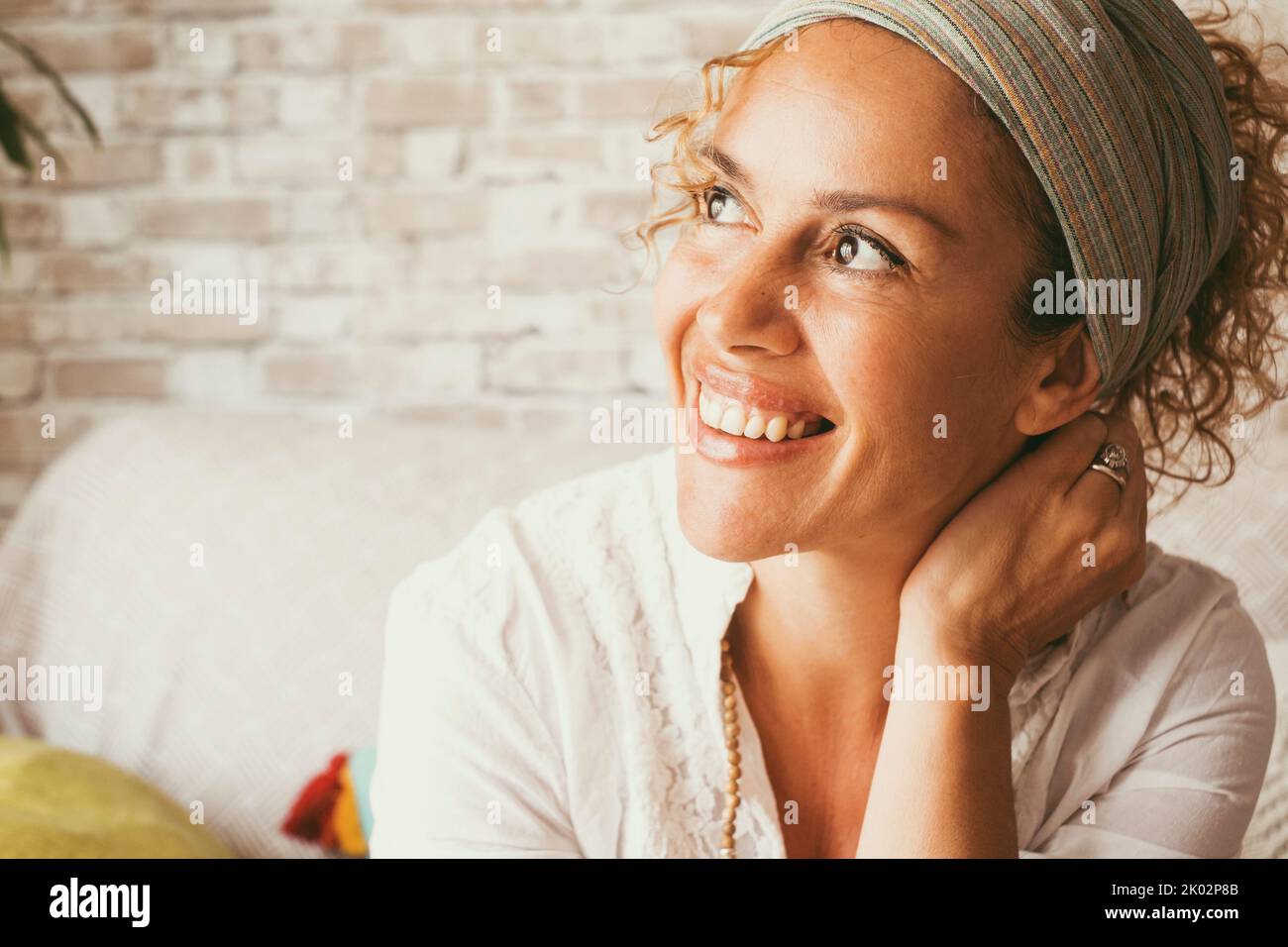 Portrait of cheerful adult woman smiling and enjoying life at home sitting on the sofa. Excited expression female people looking on her side. Attractive young lady enjoying leisure with a smile Stock Photo