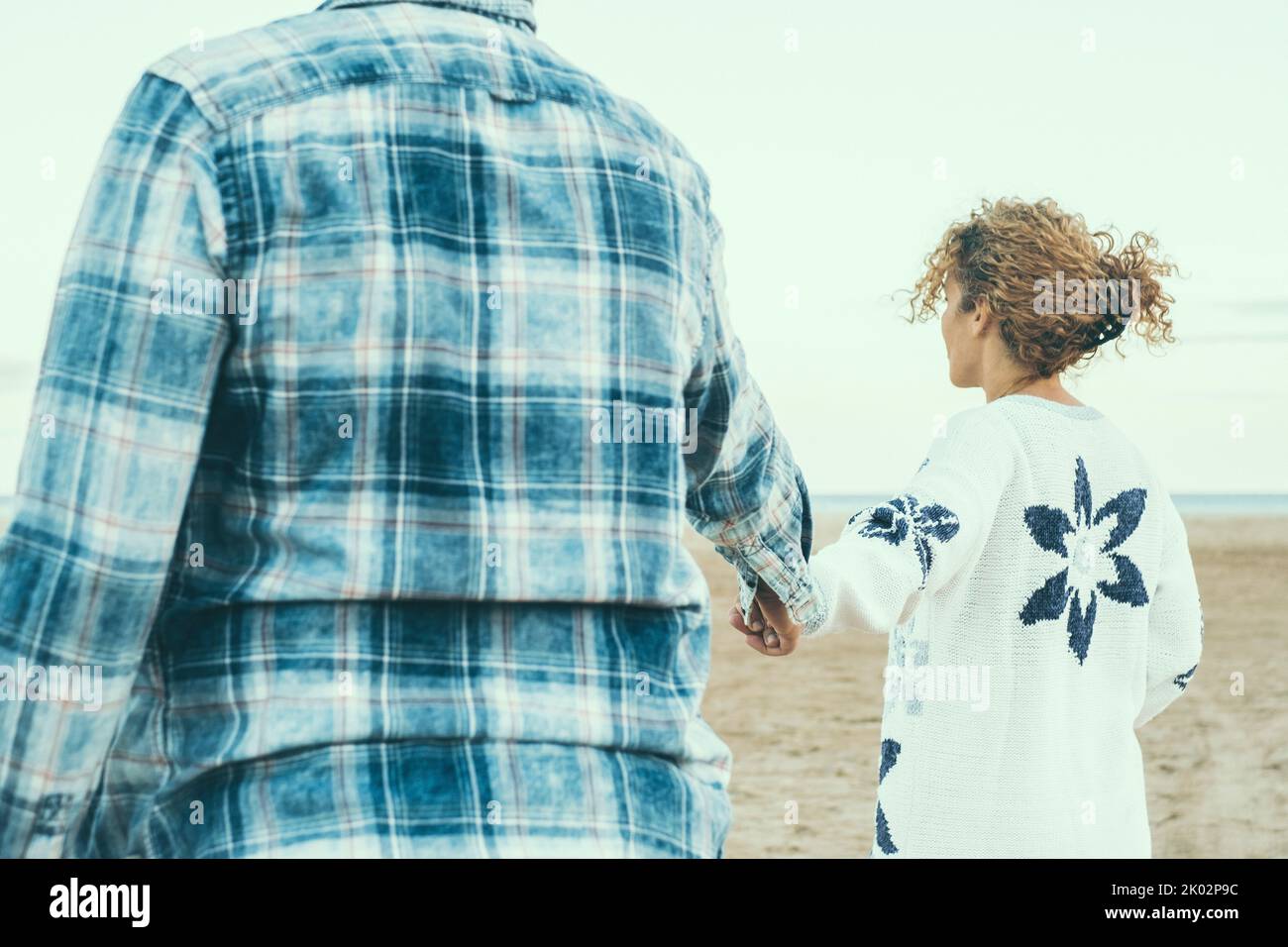 Couple summer vacation travel - Woman walking on romantic honeymoon beach holidays holding hand of boyfriend or husband following her, view from behind. POV. Outdoor leisure together Stock Photo